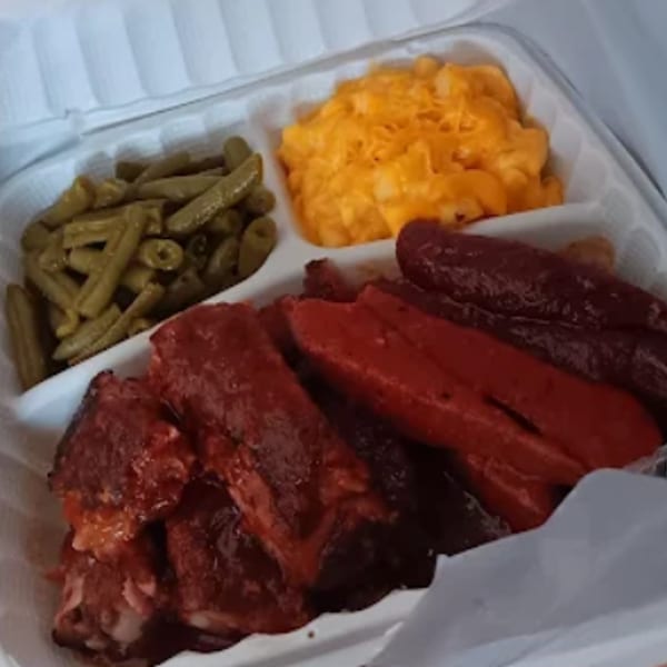 Barbecue ribs, hot dogs, green beans, and macaroni and cheese in a takeout container.
